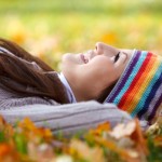 Young woman laying on dry leaves and enjoying life