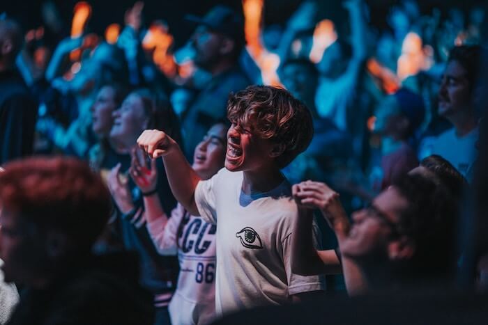 young man in large crowd singing list of emotions