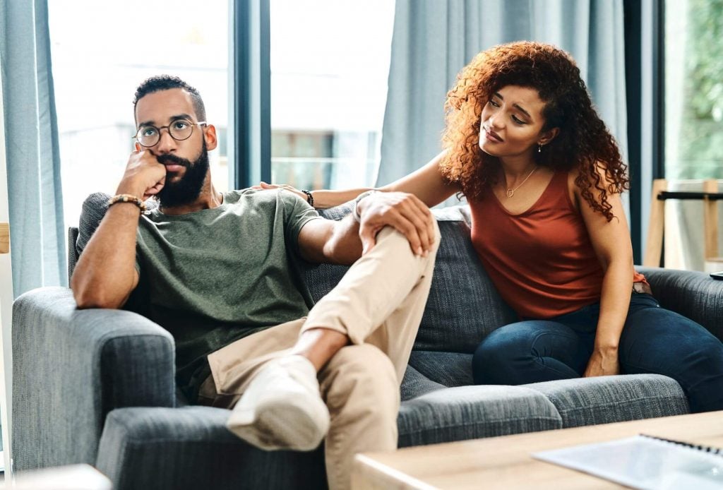 couple sitting on sofa man ignoring her Signs of Controlling Men