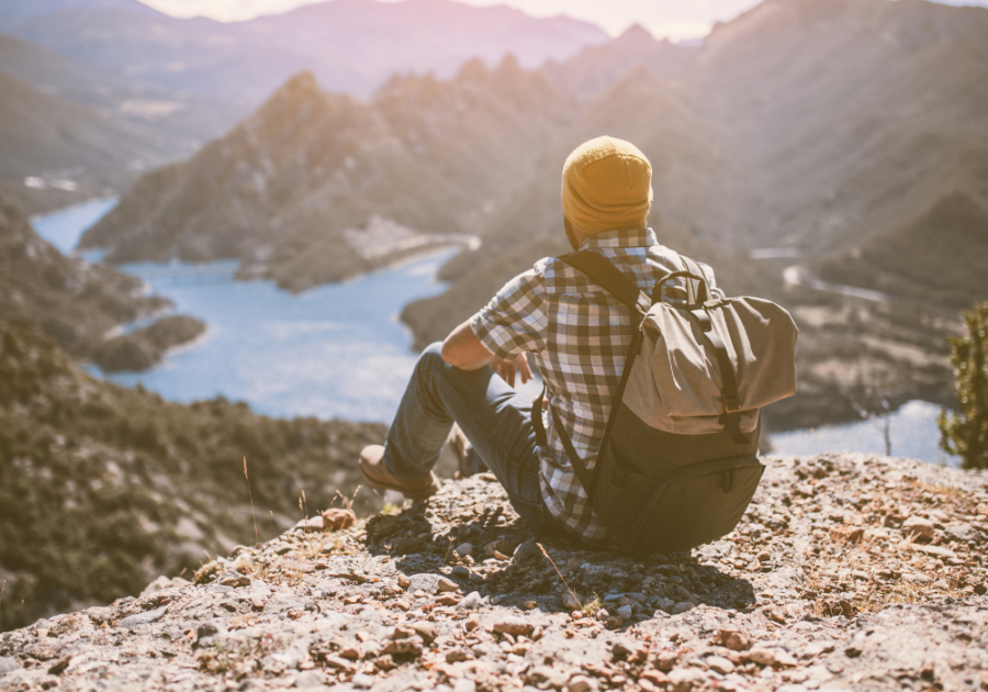 man with a backpack sitting at the edge of cliff How to be a Sigma Male