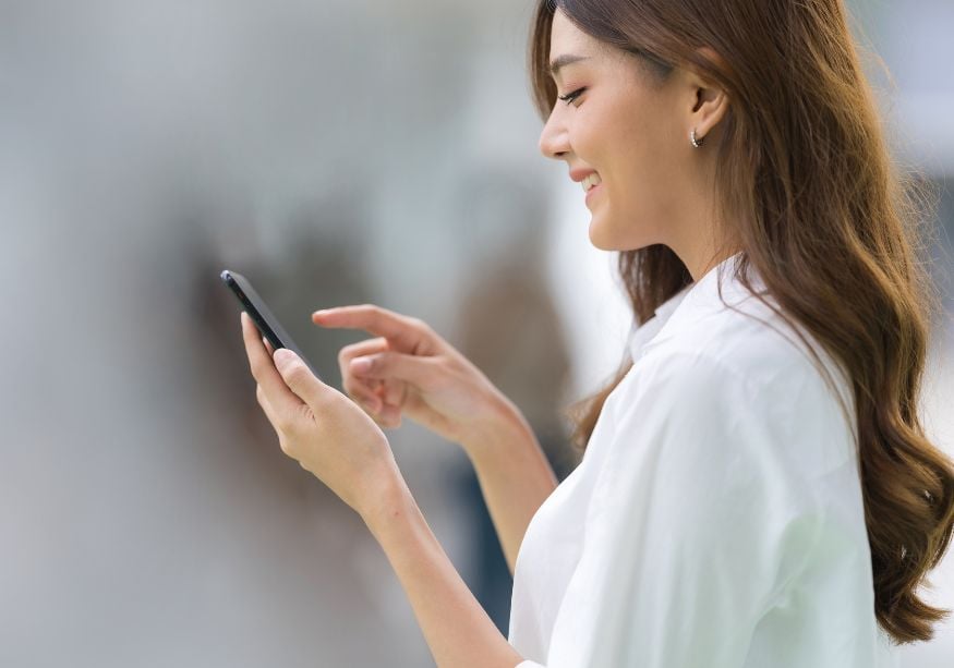 woman smiling looking at phone Good Morning Paragraphs for Her to Make Her Smile