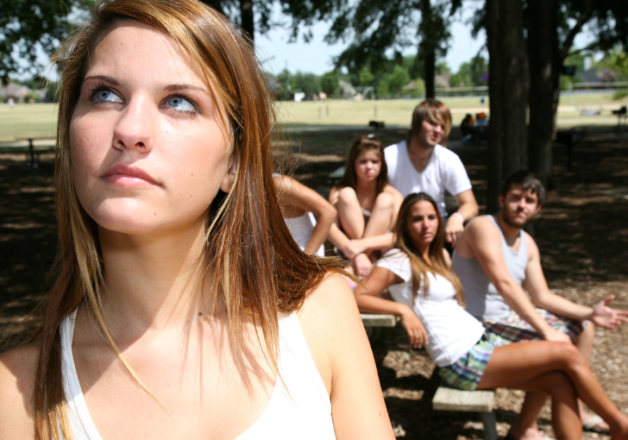 A woman standing alone looking at her in a group What happens when you ignore the manipulator