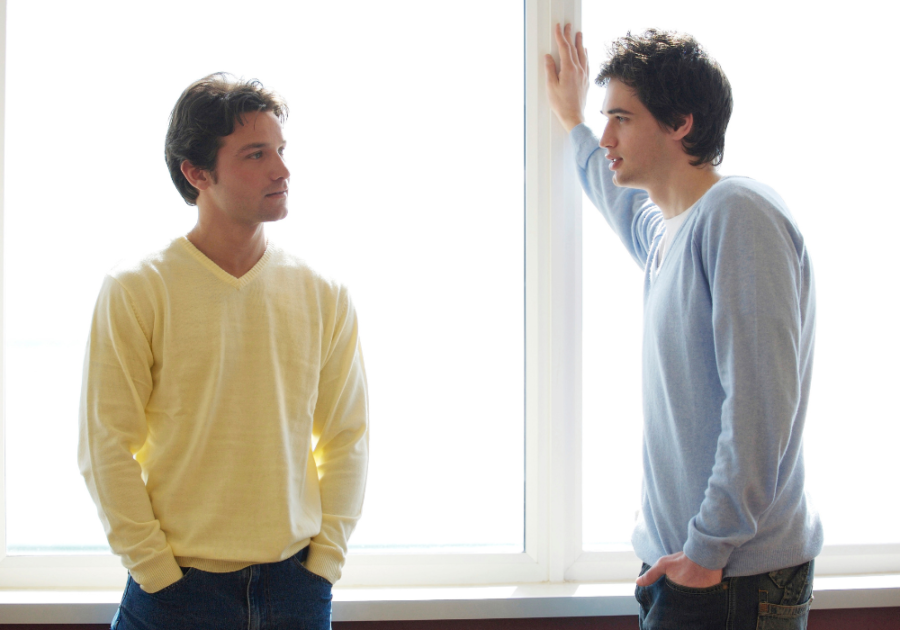 men talking standing beside large window Signs of Bisexuality in Males 