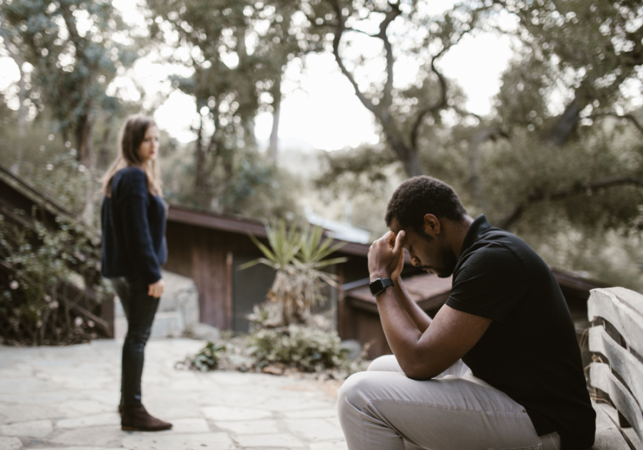 woman looking at man sitting sad How to Make a Guy Regret Ghosting You