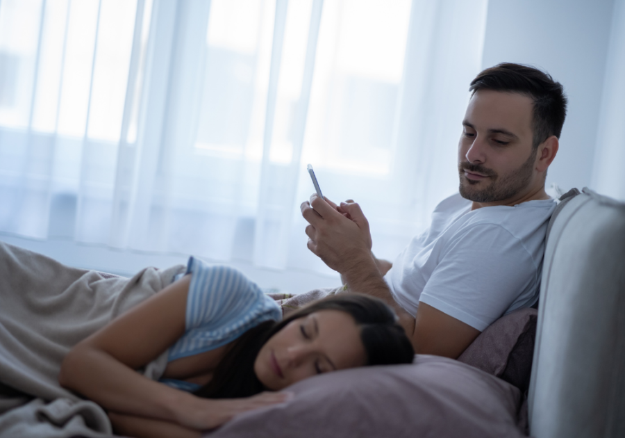 man texting while woman is asleep in bed how to heal after being cheated on