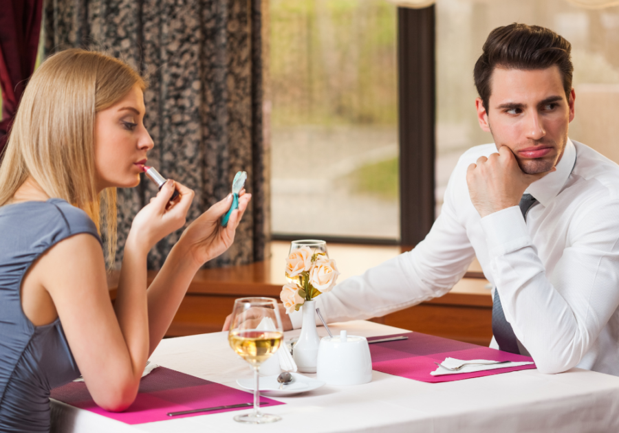 couple sitting a dinner woman putting on lip gloss dating red flags