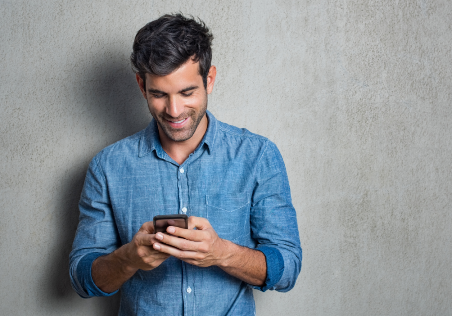 man standing by wall smiling Hinge 'Dating Me Is Like' Prompt