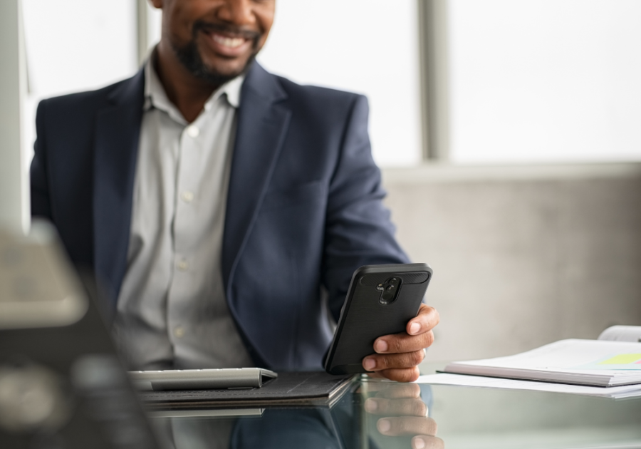 man smiling looking at phone in office Best Tinder Bios for Guys