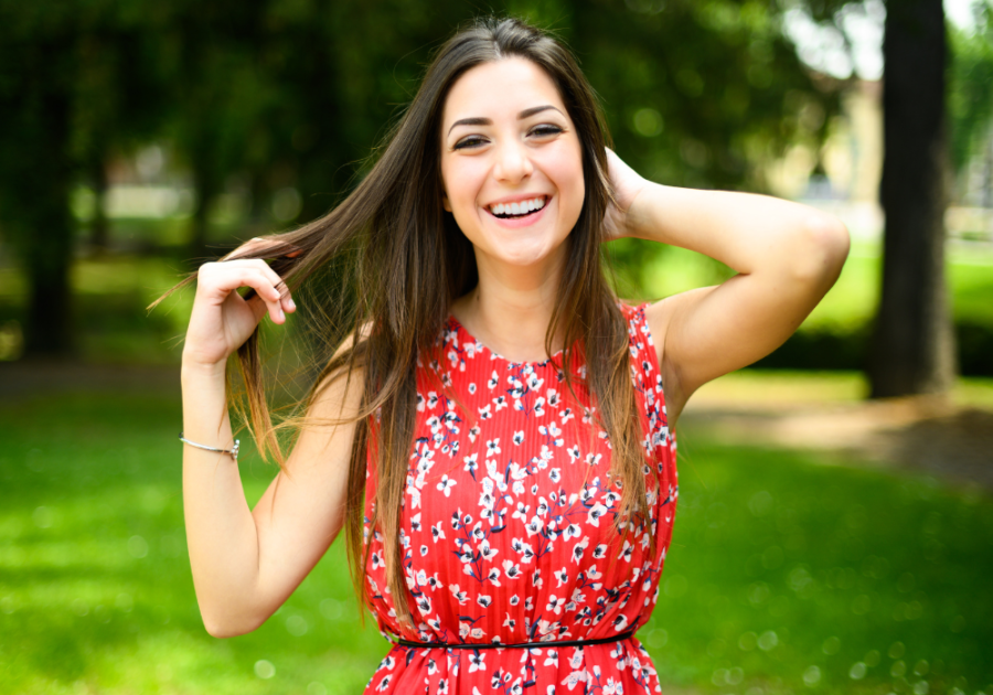 close up of woman holding her long hair smiling what does it mean when she touches her hair when she sees you?