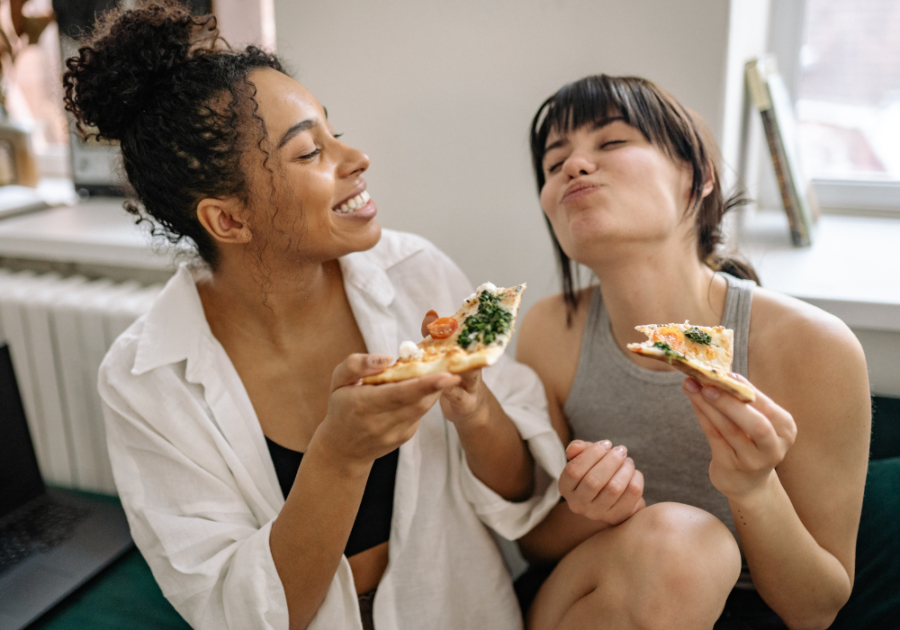 women smiling eating pizza together