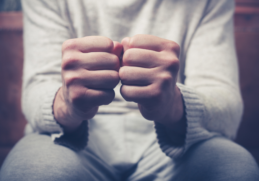 man sitting with fists clinched together insecure man