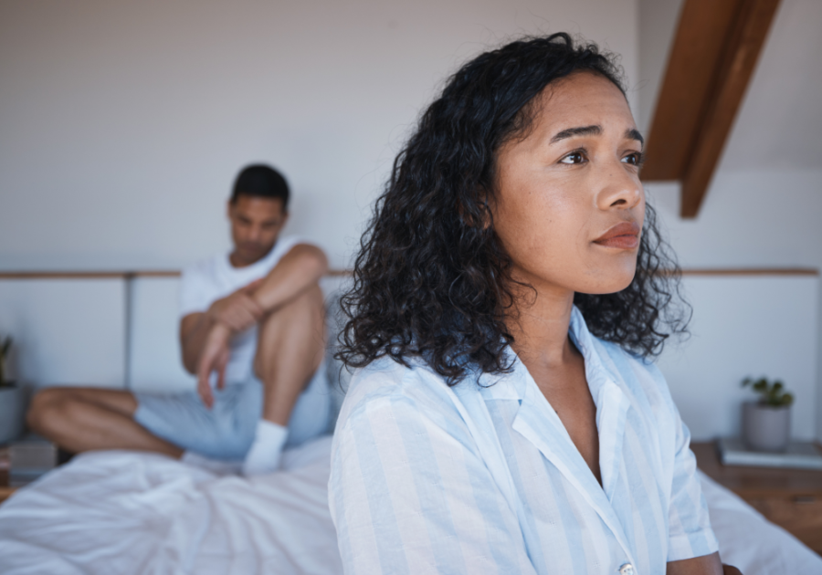 Woman sitting away from man on edge of bed