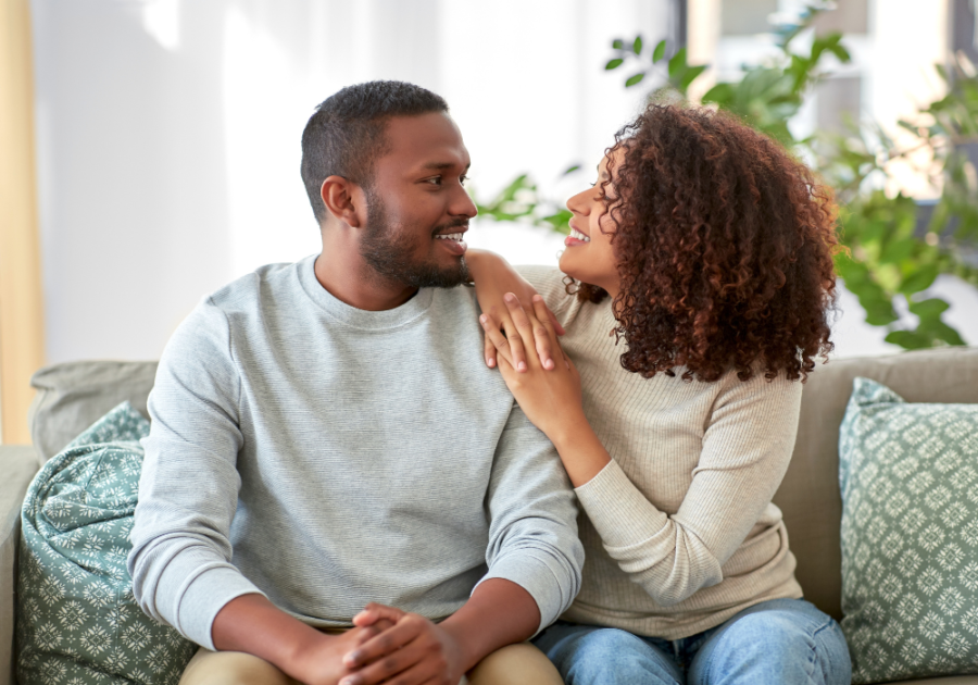 couple sitting on sofa smiling Juicy Questions to Ask Your Boyfriend