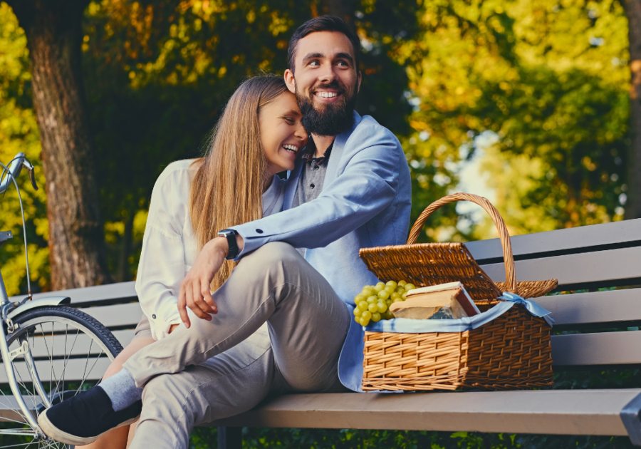 couple laughing sitting on park bench Court a Woman